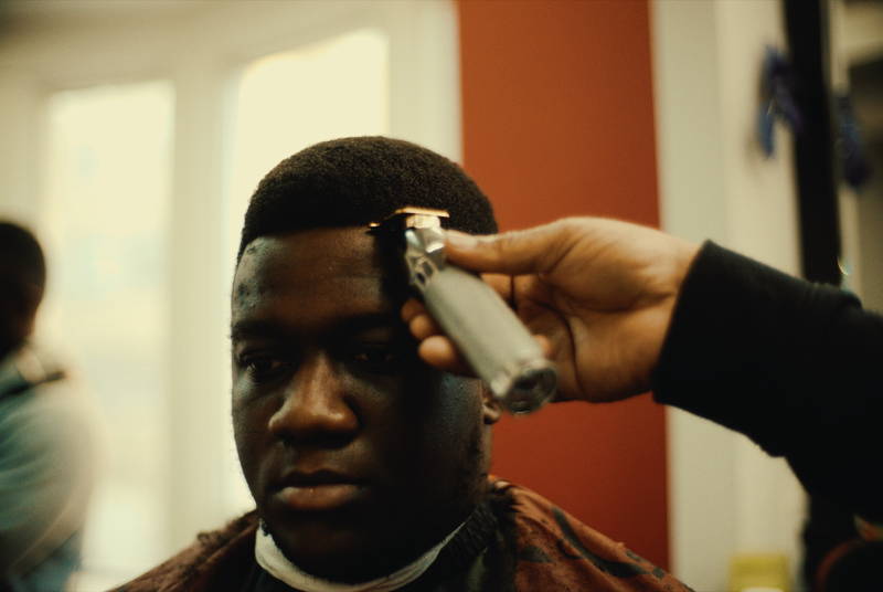 Barber lining up a client's hairline with a trimmer at RDH Barbers, a Black barbershop in Kensington Market Toronto